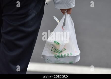 Haikou, Cina. 30 novembre 2020. Un uomo cammina tenendo in mano una borsa di plastica utilizzata presso la mensa dell'Università di Hainan a Haikou.a partire dal 1 dicembre, l'Hainan cinese vieterà la produzione, la vendita e l'uso di un'ampia gamma di prodotti di plastica monouso, secondo il dipartimento di ecologia regionale. Credit: SOPA Images Limited/Alamy Live News Foto Stock