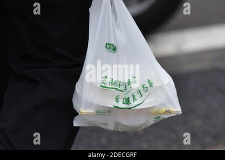 Haikou, Cina. 30 novembre 2020. Un uomo cammina tenendo in mano una borsa di plastica utilizzata presso la mensa dell'Università di Hainan a Haikou.a partire dal 1 dicembre, l'Hainan cinese vieterà la produzione, la vendita e l'uso di un'ampia gamma di prodotti di plastica monouso, secondo il dipartimento di ecologia regionale. Credit: SOPA Images Limited/Alamy Live News Foto Stock