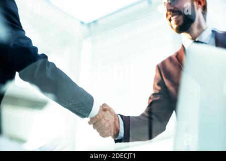 Vista dal basso. Handshake dei partner commerciali sopra la scrivania Foto Stock