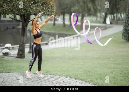 Donna atletica che pratica ginnastica ritmica con un nastro all'aperto Foto Stock