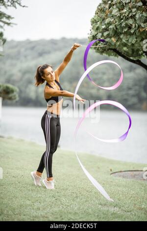 Donna atletica che pratica ginnastica ritmica con un nastro all'aperto Foto Stock