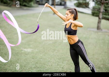 Donna atletica che pratica ginnastica ritmica con un nastro all'aperto Foto Stock