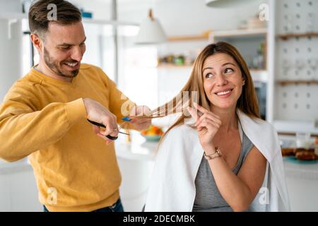 L'uomo fa un taglio di capelli alla donna a casa durante la quarantena. Foto Stock