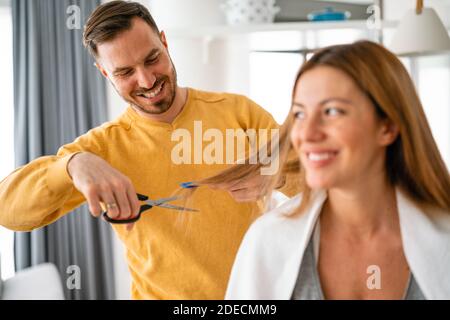 L'uomo fa un taglio di capelli alla donna a casa durante la quarantena. Foto Stock