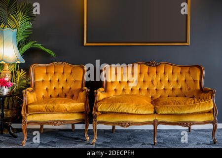 Immagine di vecchio stile, sedia giallo oro e divano in camera grigio scuro Foto Stock