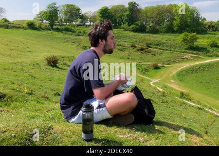 Giovane uomo che mangia al Devils Dyke appena fuori da Brighton & Hove, East Sussex, Regno Unito Foto Stock