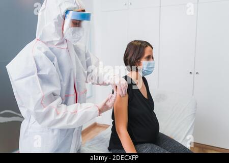 Medico che dà un vaccino ad una donna incinta contro Covid 19 o influenza o pertosse. COVID-19 vaccino del coronavirus Foto Stock