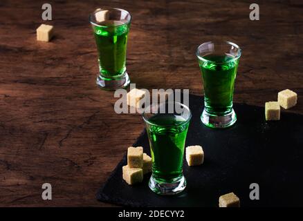 Assenzio - bevanda alcolica forte, tintura di wormwood amaro verde in bicchieri sul vecchio tavolo di legno, posto per il testo Foto Stock