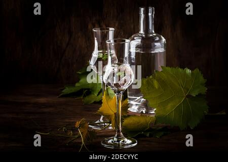 Vodka d'uva, pisco - bevanda alcolica forte peruviana tradizionale in bicchieri eleganti su tavolo di legno d'annata, spazio copia Foto Stock