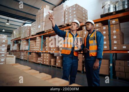 I tecnici di fabbrica esaminano le scorte presso il negozio di produzione con il digitale tablet Foto Stock