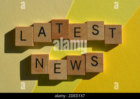 Ultime notizie, parole in lettere alfabetiche in legno isolate su sfondo giallo Foto Stock