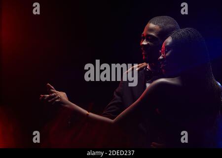Profilo di elegante coppia afro-americana che rallenta insieme in buio, spazio di copia Foto Stock