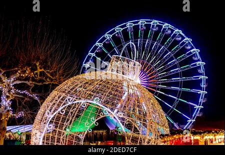 Decorazioni di Capodanno al mercato di Natale. La ruota panoramica si illumina di notte. Palla di Natale gigante e ruota panoramica. Fiera di Natale. Foto Stock