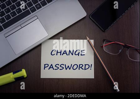 Cambiare la scheda password. Vista dall'alto dello sfondo del tavolo da ufficio con computer portatile, telefono, occhiali e matita con scheda con iscrizione cambia password. Foto Stock
