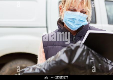 Consegna servizio pacchi con maschera controlla consegna con la guida di list Foto Stock