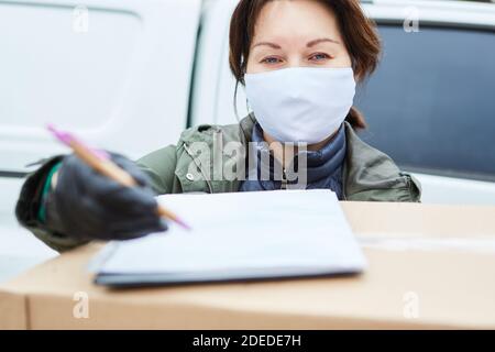 Consegna il servizio di trasporto pacchi con maschera facciale richiede l'accettazione conferma mediante firma Foto Stock