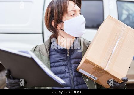 Servizio di consegna pacchi con maschera consegna pacchi e. si guarda intorno Foto Stock