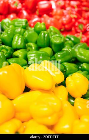 una pila di peperoni dolci rossi, verdi e gialli come sfondo. immagine verticale Foto Stock