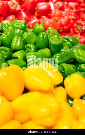 una pila di peperoni dolci rossi, verdi e gialli come sfondo. immagine verticale Foto Stock