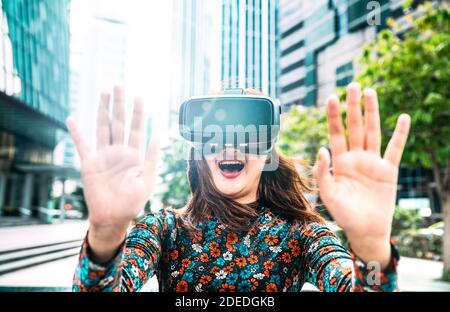 Giovane donna asiatica che sperimenta gli occhiali vr nella città moderna - Realtà virtuale e concetto tecnologico indossabile con la ragazza che si diverte con occhiali di protezione Foto Stock