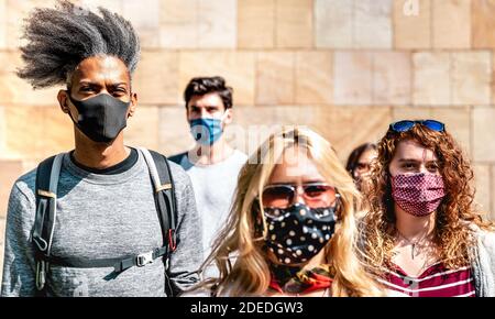 Folla multirazziale che cammina vicino al muro nel contesto urbano della città - Nuovo concetto di stile di vita normale con i giovani coperti da protezione maschera facciale Foto Stock