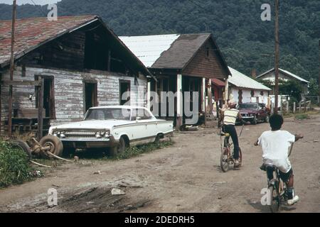 1970 Foto (1973) - Rand WV; con la maggior parte della sua popolazione che vive in povertà ha molte strade non asfaltate -case di livello inferiore e automobili sommerse Foto Stock