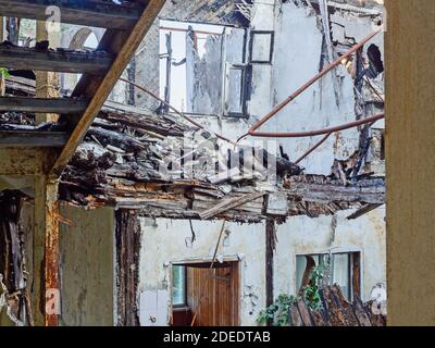 Rovine di un edificio di appartamenti con una scala di ferro e. un mucchio di detriti di legno di carred Foto Stock