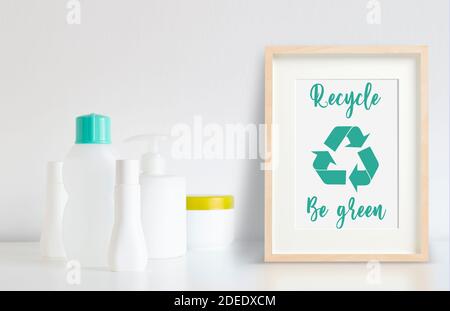 Alcune bottiglie di plastica pronte per essere riciclate accanto a una cornice con logo di riciclo. Foto Stock