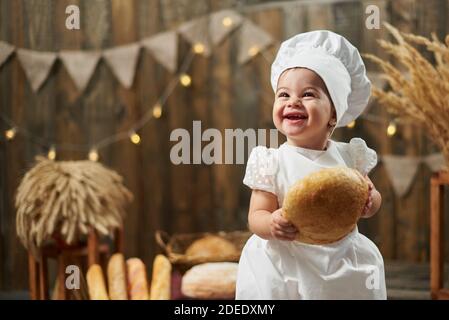 Buon panettiere del bambino che tiene il pane e sorride Foto Stock