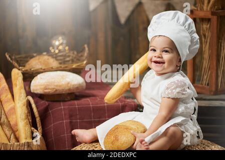 Buon panettiere del bambino che tiene il pane e sorride Foto Stock