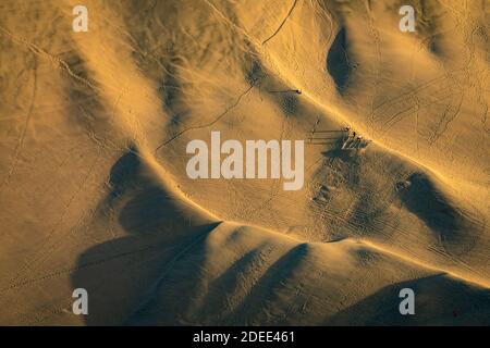 Vista ad alto angolo della gente sandboarding in dune da Huacachina oasi prima del tramonto, Ica, Perù Foto Stock