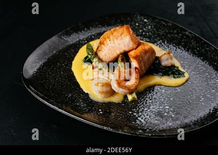 salmone alla griglia e gamberi su sfondo nero Foto Stock