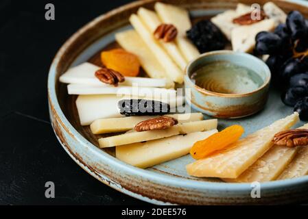 piatto di formaggi con una varietà di formaggi su un nero sfondo Foto Stock