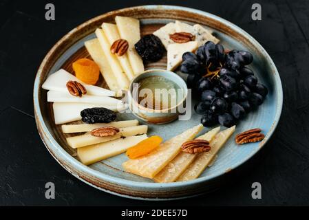 piatto di formaggi con una varietà di formaggi su un nero sfondo Foto Stock