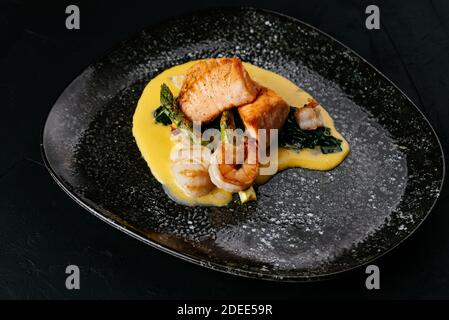 salmone alla griglia e gamberi su sfondo nero Foto Stock