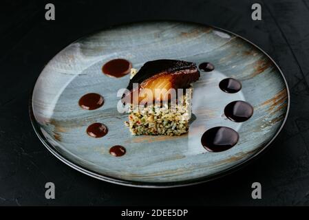 pesce alla griglia con riso e verdure su sfondo nero Foto Stock