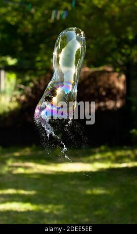 Bolla di sapone a scoppio singolo all'esterno, alta velocità dell'otturatore. La bolla esplode all'esterno a mezz'aria, movimento congelato. Fallimento, stress psicologico, salute mentale Foto Stock