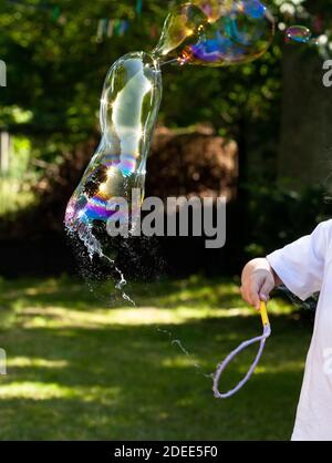 Bolla di sapone semplice e scoppiante all'esterno, alta velocità dell'otturatore. Bolle scoppiare all'esterno a mezz'aria, movimento congelato fallire, stress psicologico, salute mentale Foto Stock