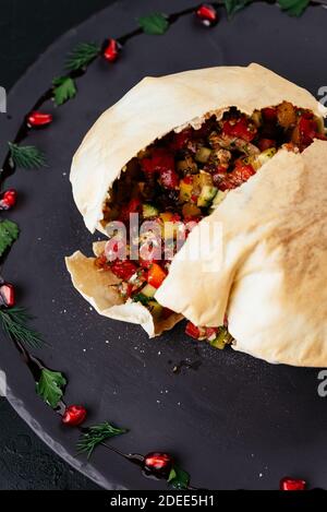 Insalata di verdure georgiane in pane di tortilla su sfondo nero Foto Stock