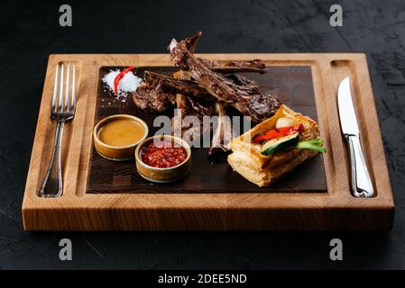 griglia di agnello con verdure e salsa su un nero sfondo Foto Stock