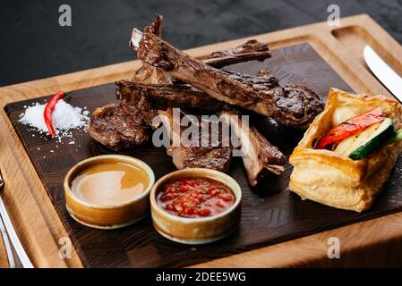 griglia di agnello con verdure e salsa su un nero sfondo Foto Stock