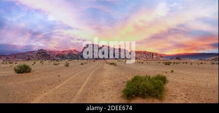 Vista panoramica sul deserto di sabbia rossa con un tramonto dorato nuvoloso a Wadi Rum, Giordania Foto Stock