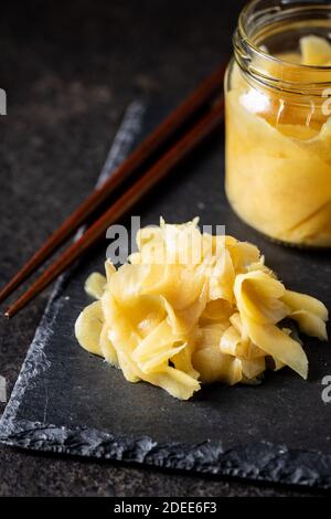 Fette di zenzero di sushi sottaceto su tagliere di pietra nera. Foto Stock