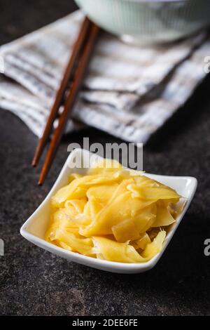 Fette di zenzero di sushi sottaceto in ciotola su tavola nera. Foto Stock