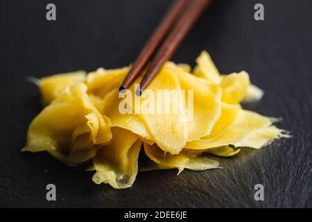 Fette di zenzero di sushi sottaceto su tagliere di pietra nera. Foto Stock