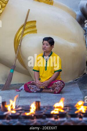 Uomo seduto accanto alla scopa con fiamme di offerte candele a Shwedagon Pagoda, Yangon, Myanmar (Birmania), Asia nel mese di febbraio Foto Stock