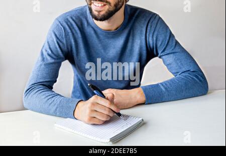 Primo piano uomo mani scrivere gli obiettivi per il nuovo anno 2021. Scrivete una lista dei desideri a Babbo o degli obiettivi per il concetto di Capodanno. Messa a fuoco selettiva Foto Stock