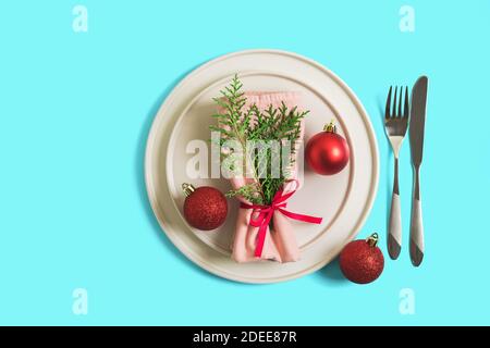 Tavolo servito con piatto e posate per la celebrazione di Natale e Capodanno. Sul piatto è un tovagliolo con albero di Natale ramo, palline rosse. Flatlay ON Foto Stock