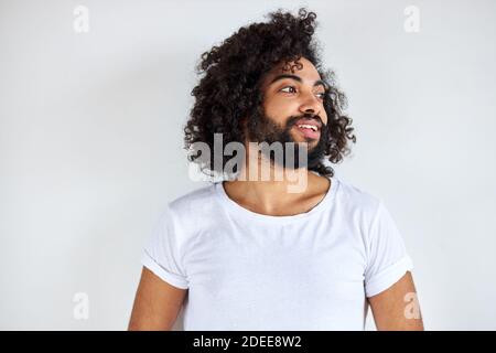 ritratto di allegro positivo maschio di aspetto arabico guardando via ridendo, ascolta scherzo, divertirsi con qualcuno, isolato su sfondo bianco Foto Stock