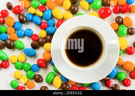 Tazza di caffè nero e caramella al cioccolato su sfondo bianco, caramelle colorate Foto Stock